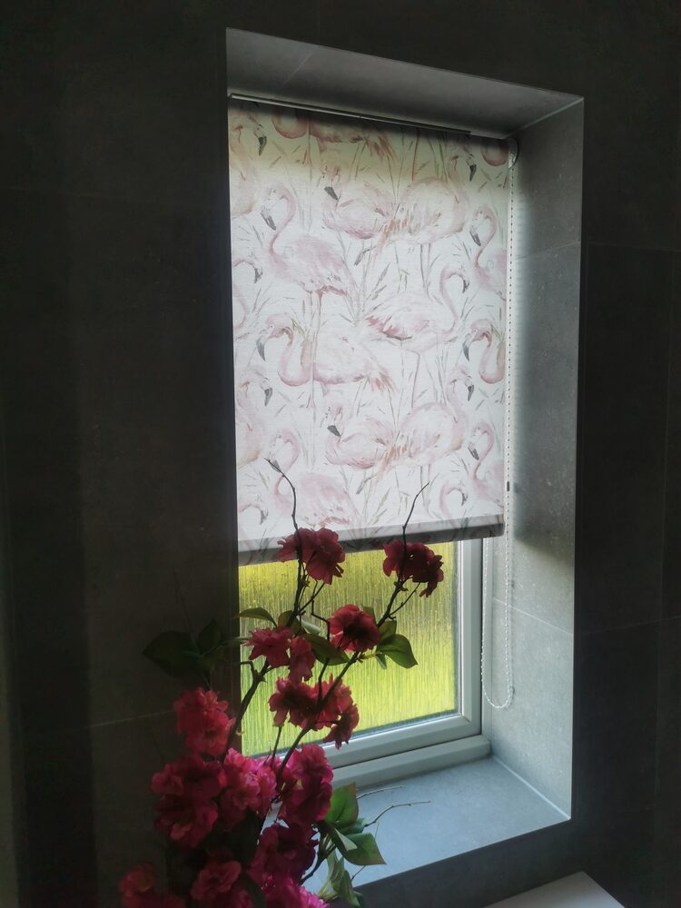 Patterned roller blind with flamingo design in a cloakroom window