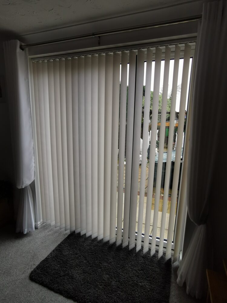 White vertical blinds fitted to patio doors in a living room
