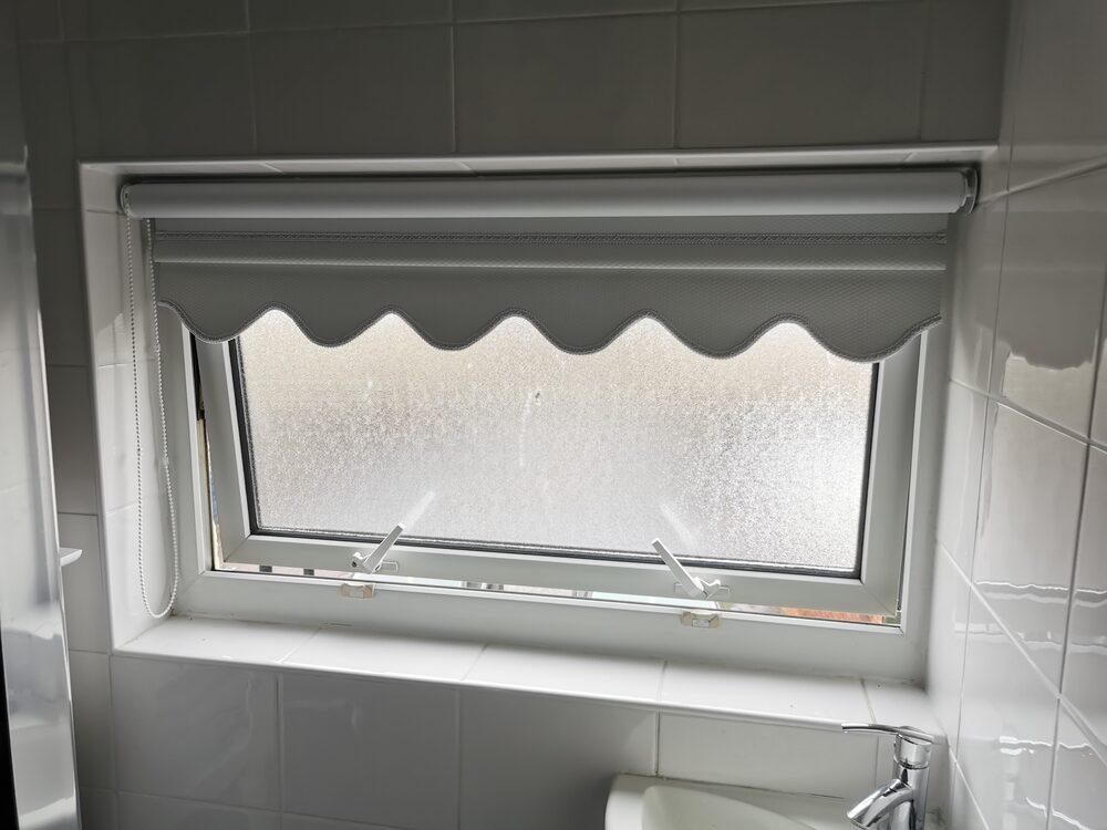 Scallop-edged blackout roller blind in a bathroom window